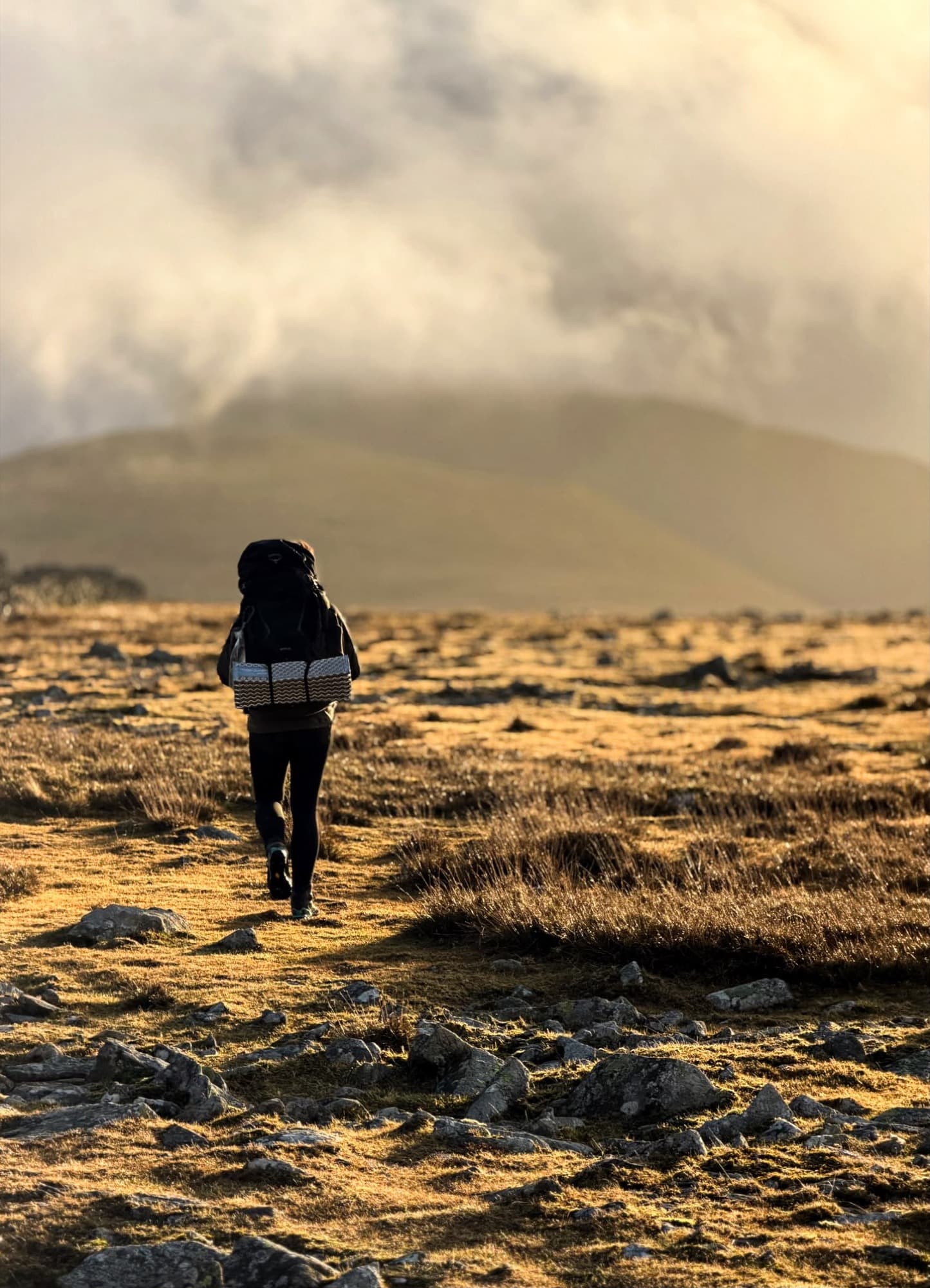 Robyn hiking with a full pack in golden evening light