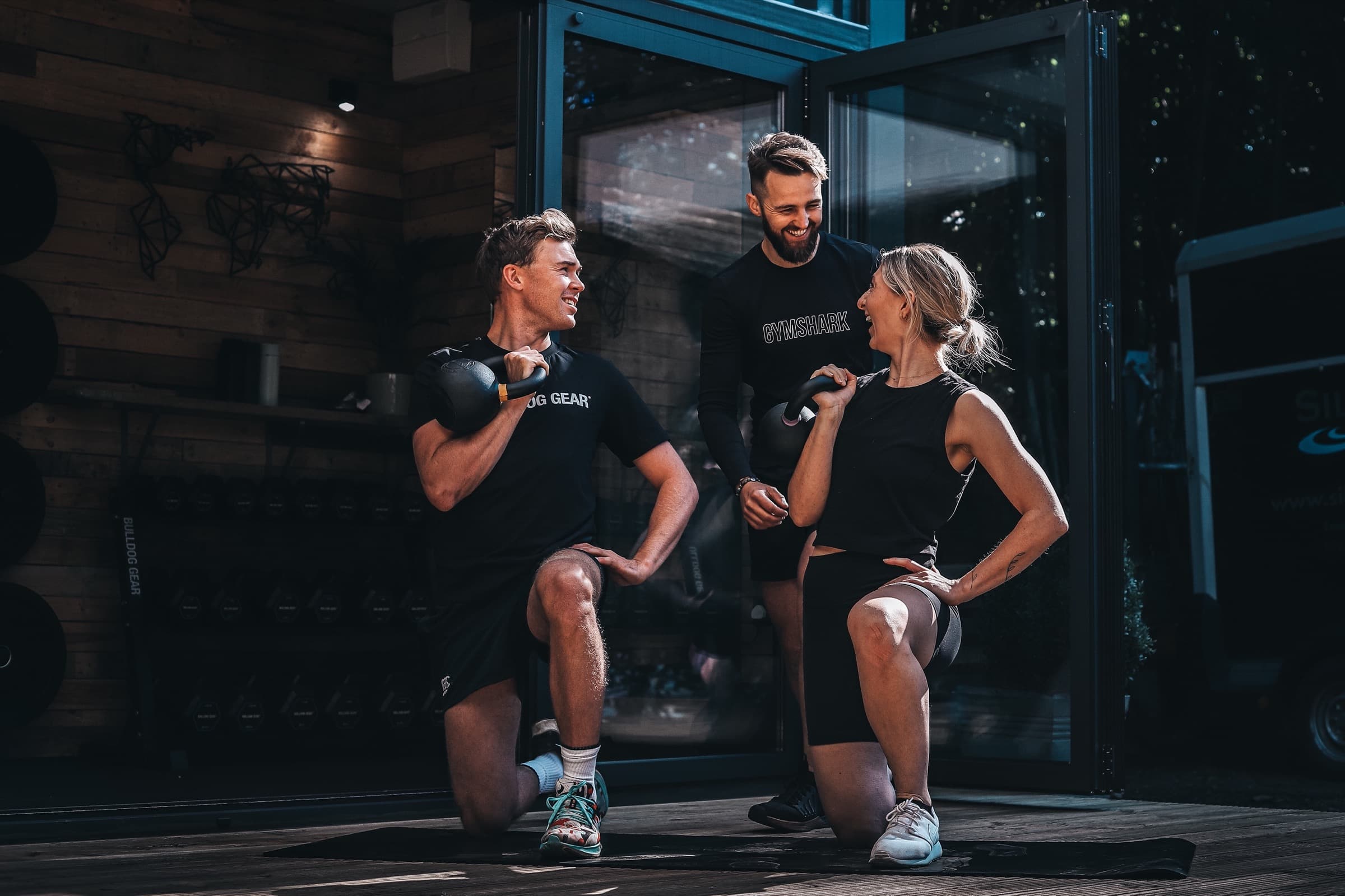 Three people training with kettlebells on the deck outside the Yard Fitness studio